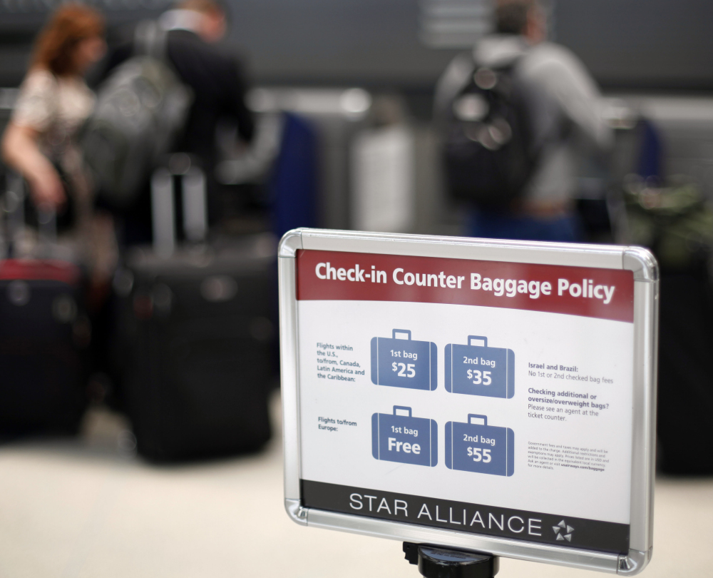 A sign describes an airline’s baggage fees at Philadelphia International Airport. But the cost of flight cancellation or change fees are sometimes hidden in a ticket’s fine print.