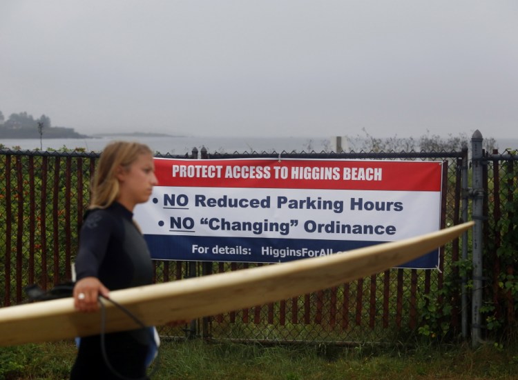 A surfer walks to the beach past a political sign along Bayview Avenue in Scarborough last month. Scarborough Council dropped a proposal by property owners who wanted to make it illegal to change clothing in areas adjacent to the beach.