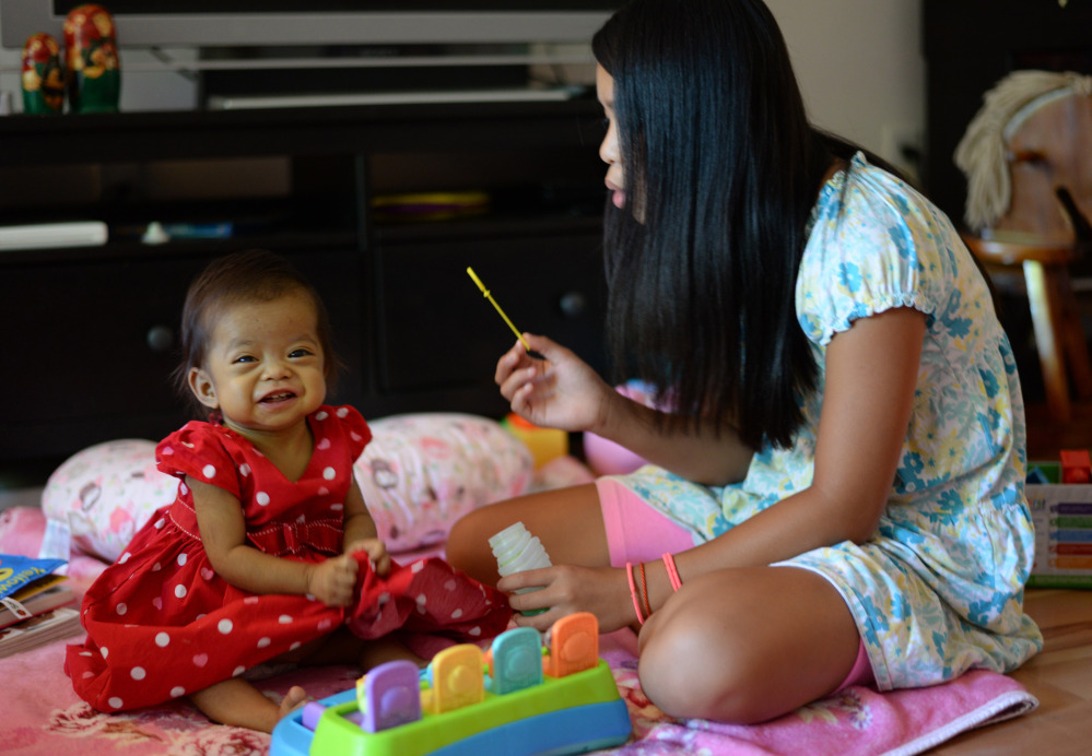 Hope Morrison, 17 months, plays with her sister Lianna, 10, last month at their home in Andover, Mass.  A few months ago, Hope was an underdeveloped, emaciated baby living with end-stage liver failure in a Chinese orphanage.