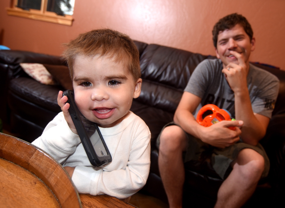 Liam Maddox, left, a heart transplant recipient, plays with a phone as his father, Paul Maddox, looks on at their home in Edgemont Ranch northeast of Durango, Colo.