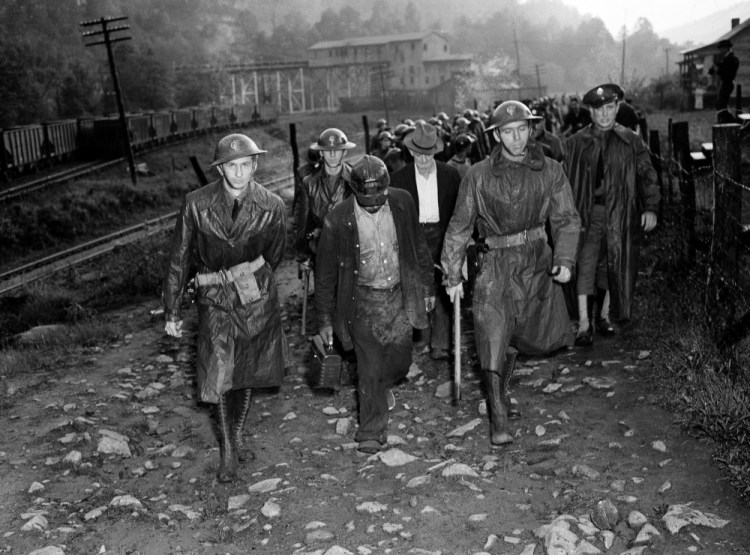 On May 16, 1939, their day’s work done, miners who reported for duty for the Harlan Central Coal Co. near Harlan, Ky., leave the mine under the guard of troops who escorted them through a picket line.