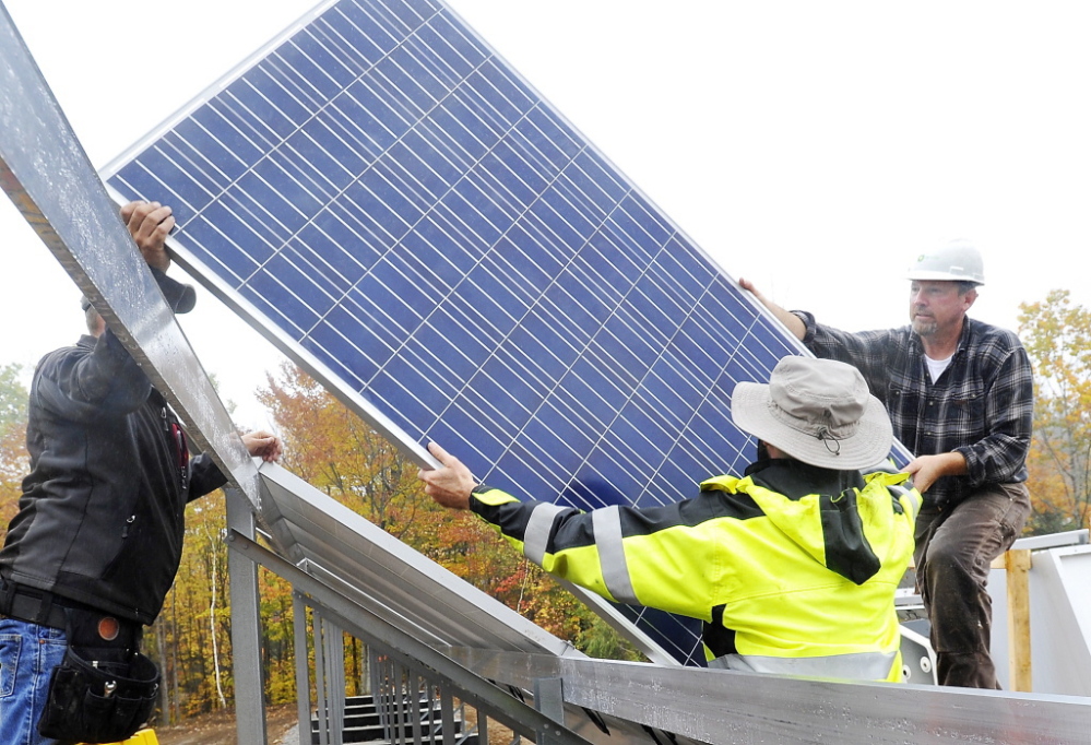 Workers install a solar electric panel in a ground-mounted solar array for Mt. Abram ski resort, similar to the solar array that is planned for a community solar farm in Wayne.