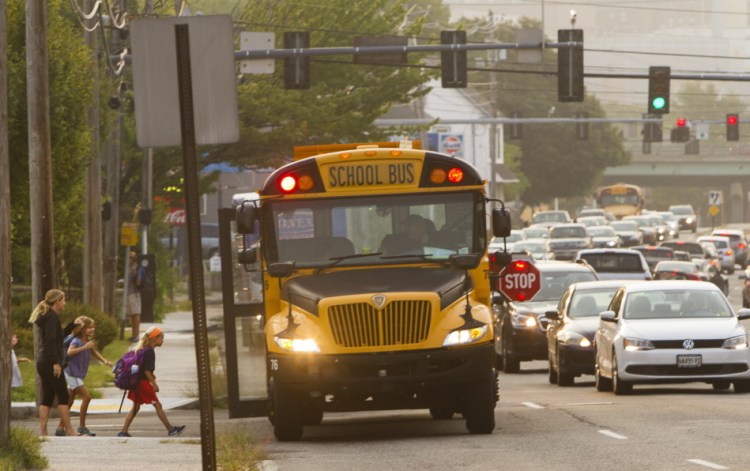 Children board their school bus Thursday, under the supervision of parents, at the stop at Frances and Congress streets in Portland. A change in school start times led to the relocation of some bus stops to main streets with heavy morning commuter traffic.