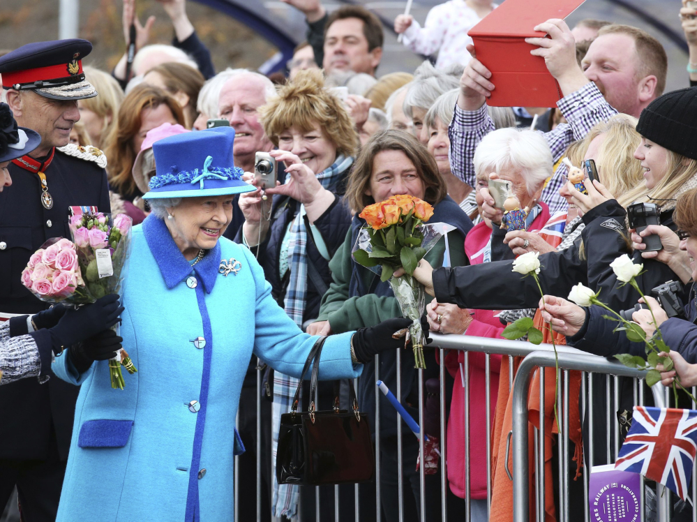 Britain’s Queen Elizabeth II, on the day she became Britain’s longest reigning monarch, accepts flowers from onlookers as she arrives to inaugurate the new multimillion-pound Scottish Borders Railway, at Tweedbank, Scotland, on Wednesday.