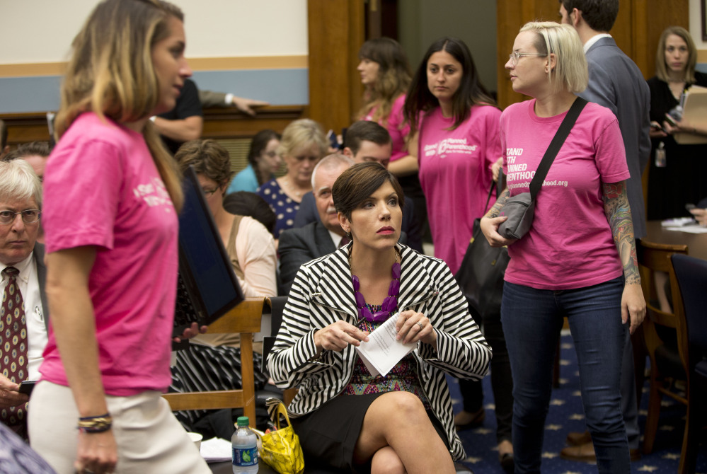 As supporters of Planned Parenthood looks for seats, anti-abortion activist Melissa Ohden, center, waits to testify before the House Judiciary Committee hearing at the Capitol in Washington examining the abortion practices of Planned Parenthood.