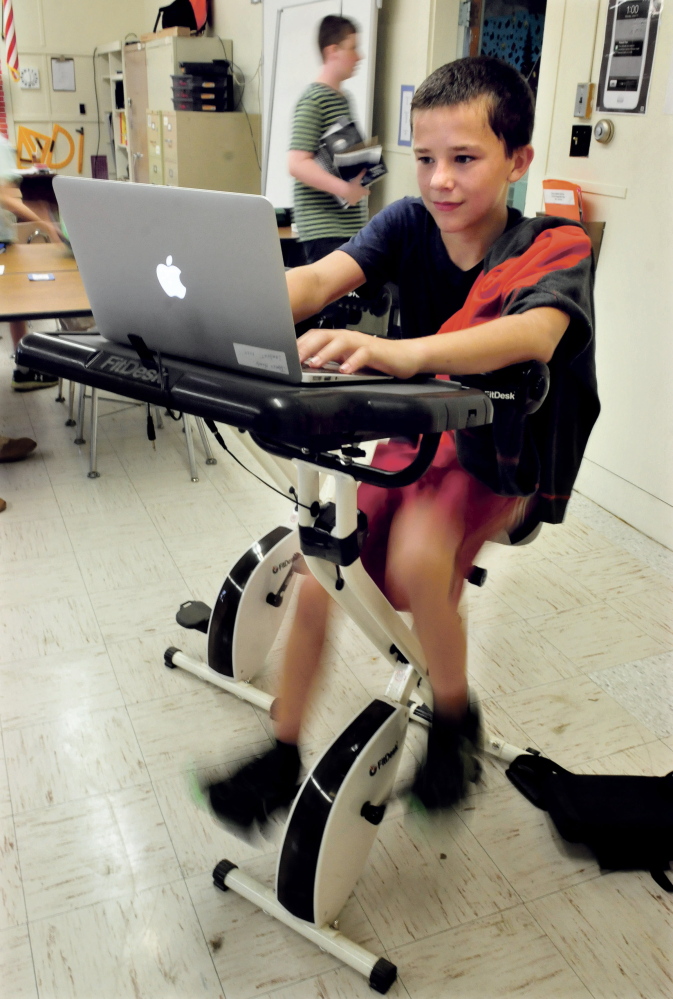 China Middle School student James Hardy pedals a bike while working on his laptop during math class Wednesday.
