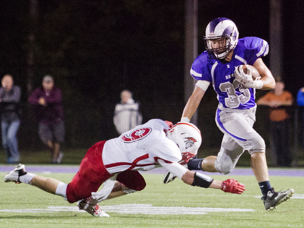 Deering's Rob Dacey keeps Sanford defensive back Peter Hegarty at bay with a stiff arm in the first half Friday. Gabe Souza/Staff Photographer