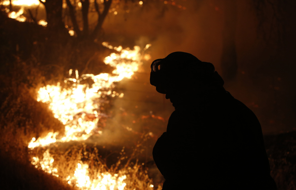 A firefighter turns his head from the flame of the Butte Fire burning near San Andreas, California, on Friday.