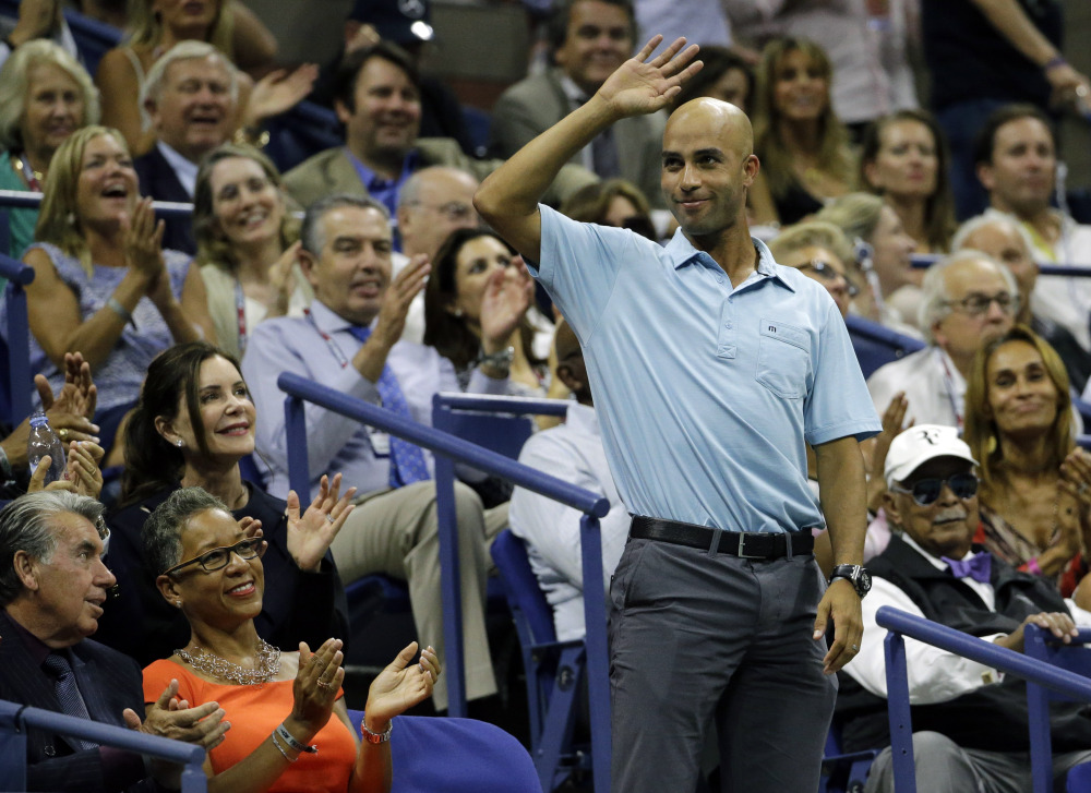 Former tennis pro James Blake, right, acknowledges applause during a semifinal match between Roger Federer and Stan Wawrinka at the U.S. Open on Friday.