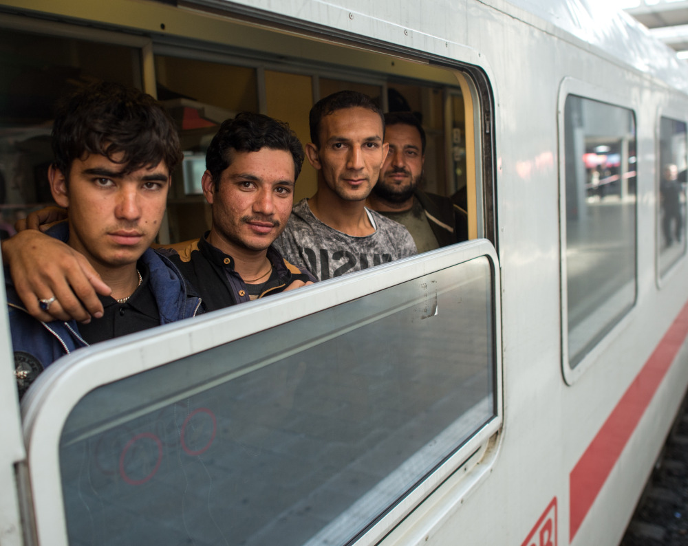 Friends Ibrahim, Hamayoun and Nomi, from left, refugees from Afghanistan, travel on a special train to Dortmund at the central train station in Munich, Germany, on Friday.
