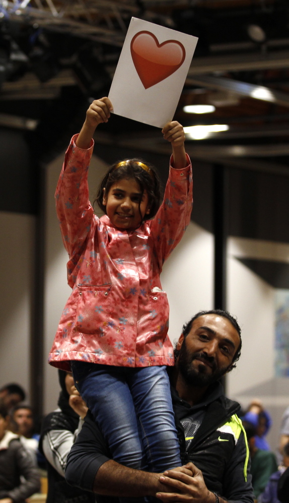 A Syrian father holds up his daughter at a reception center after their arrival at the main railway station in Dortmund, Germany, on Sunday.