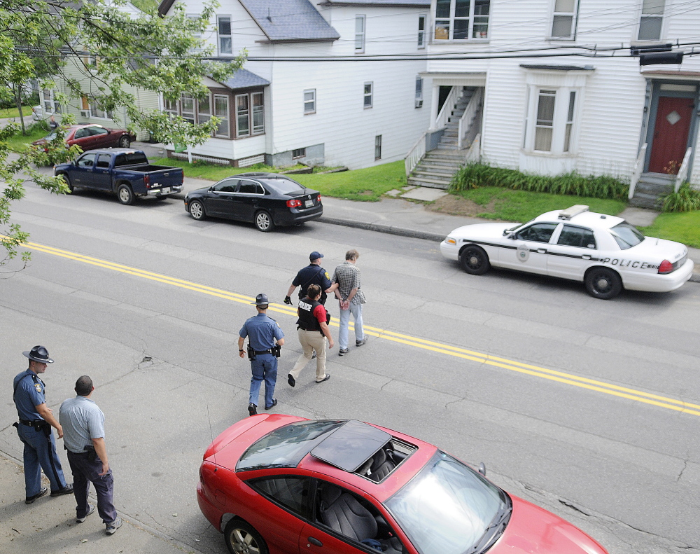 An Augusta police detective, Maine State Police troopers and parole and probation officers escort a man arrested on outstanding warrants to a waiting cruiser on Northern Avenue in Augusta on July 30. State and county law enforcement officers accompanied Augusta police in door-to-door walks through several neighborhoods in Augusta as part of the city Police Department’s Operation Hot Spot program.