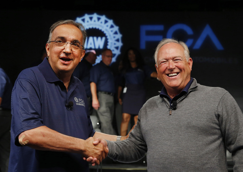 Fiat Chrysler Automobiles CEO Sergio Marchionne, left, and United Auto Workers President Dennis Williams shake hands during a ceremony to mark the opening of contract negotiations in Detroit in July. (AP file photo/Paul Sancya)