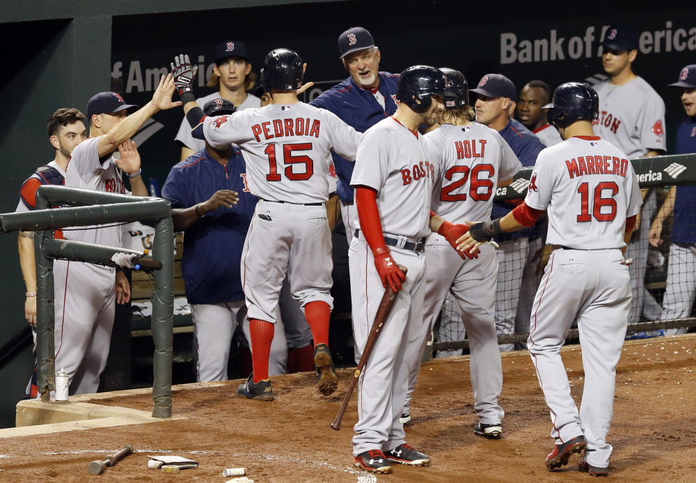 Boston's Dustin Pedroia (15) high-fives teammates in the dugout after driving in Brock Holt (26) and Deven Marrero (16) on a three-run home run in the fourth inning against Baltimore on Wednesday in Baltimore. The Associated Press 