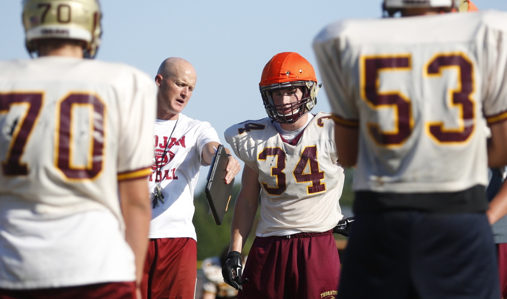 Owen Elliott, a linebacker and senior co-captain for Thornton Academy, receives instruction from Coach Kevin Kezal. The coach of the defending state champions tries to make sure nonstarters get plenty of chances as underclassmen, a strategy that continues to pay off.