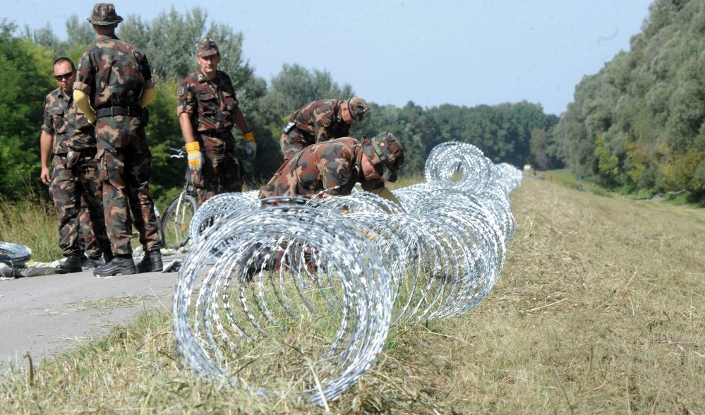 Hungarian soldiers set up razor wire, the first line of a temporary fence under construction on Hungary’s southern border with Croatia designed to halt illegal migrants.