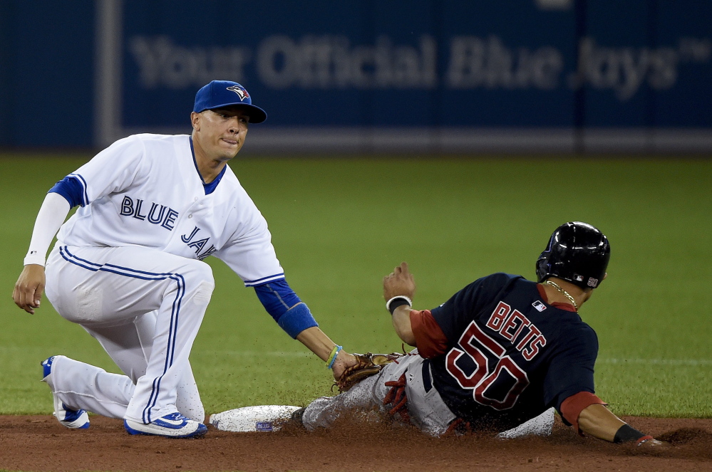 Boston Red Sox’s Mookie Betts (50) is tagged out at second base by Toronto Blue Jays shortstop Ryan Goins on an attempted steal during the second inning Friday in Toronto.