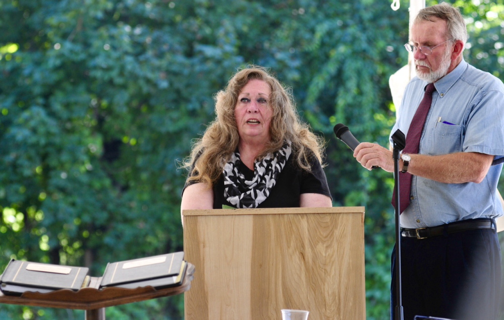 Karen Evans speaks as Peter Driscoll holds the microphone during Friday’s dedication of a new monument to honor those who died while at the Augusta Mental Health Institute.