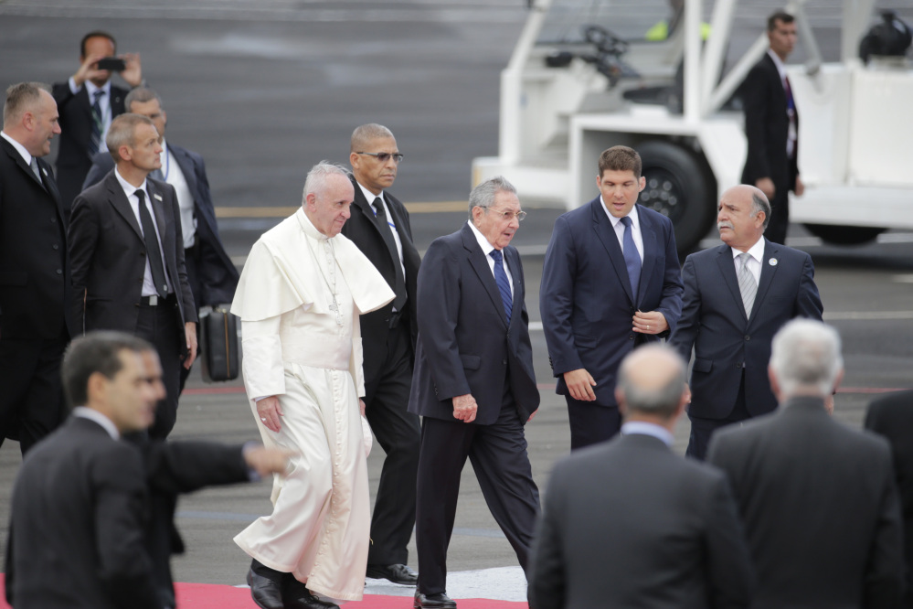 Surrounded by security, Pope Francis walks with Cuba’s President Raul Castro as he arrives in Havana, Cuba, Saturday.
