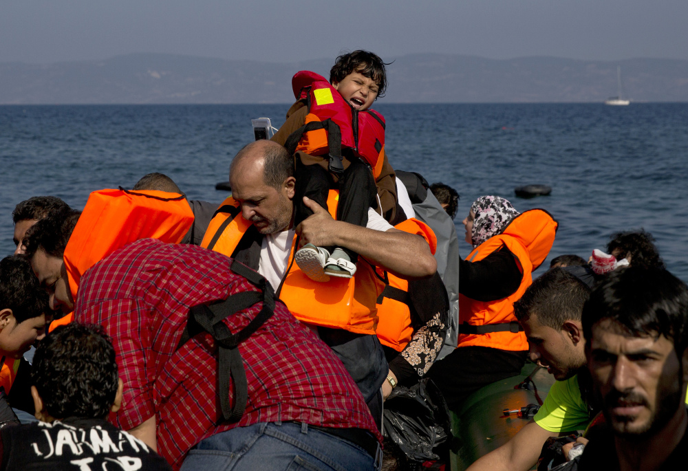 Migrants arrive aboard a dinghy after crossing from Turkey to the island of Lesbos, Greece, on Sunday. A boat with 46 migrants or refugees has sunk Sunday in Greece and the coast guard says it is searching for 26 missing off the eastern Aegean island of Lesbos.