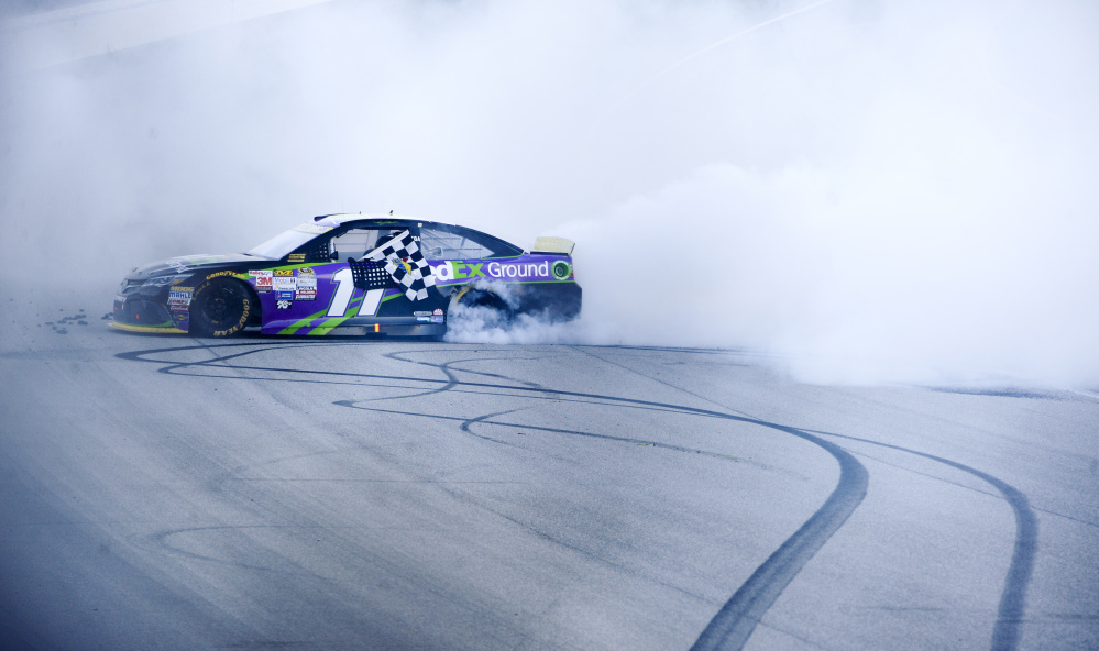 Denny Hamlin does a burnout after winning Sunday’s Sprint Cup race at Chicagoland Speedway. Hamlin is assured of a spot in the second three-race segment of the Chase for the Sprint Cup championship.