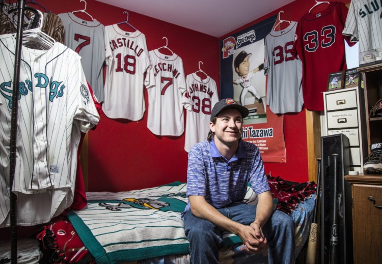 Joey Morrill, a senior chemistry major at the University of Southern Maine, sits amid the Sea Dogs memorabilia displayed in the room of his brother, Dom, 15. Collecting game-worn jerseys is “almost like a hunt to see which one you can get next,” Morrill said.