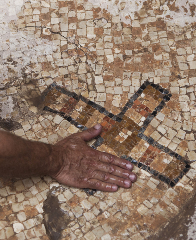 A worker for the Israel Antiquities Authority shows a cross on a mosaic floor at the archaeological site at Ben Shemen Forest.