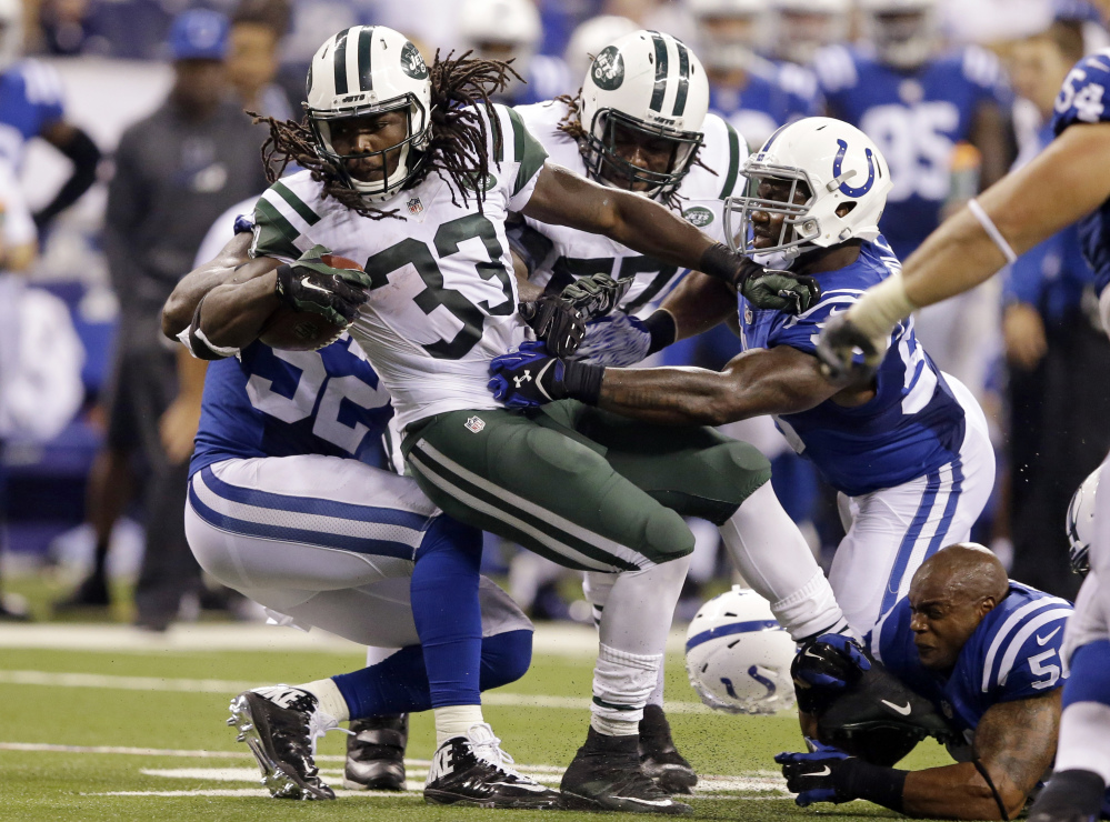 Colts linebacker Jerrell Freeman, bottom right, loses his helmet as he helps tackle Jets running back Chris Ivory, 33, during a 20-7 win by the Jets at Indianapolis on Monday.
