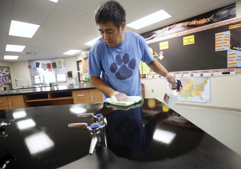 Lodel Seneres, a custodian at Saco Middle School, wipes down countertops in a science classroom.