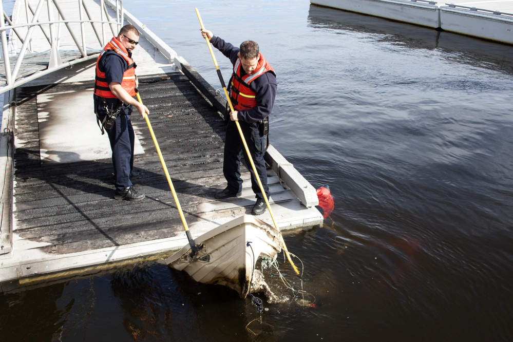 Bath Fire Department officers fish the remains of a dinghy from the Kennebec River in Bath after it was destroys in a fire Thursday night.