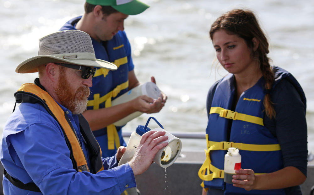 In this Tuesday, Sept. 15, 2015 photo, Thomas Bridgeman, an associate professor in the Department of Environmental Sciences at the University of Toledo, left, along with graduate students Kristen Hebebrand and Ken Gibbons, gather water samples from Lake Erie near the City of Toledo water intake crib, approximately 2.5 miles off the shore of Curtice, Ohio. In the wake of Toledo’s water crisis, Ohio has put limits on when and where farmers can spread fertilizer and manure on fields. (AP Photo/Haraz N. Ghanbari)