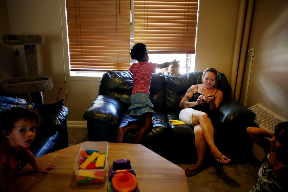 ADVANCED FOR RELEASE SATURDAY, SEPTEMBER 26, 2015 Maria Santos, right, relaxes in her apartment with her children and friends, including Kathryn Tinsley, 8, at the Bunker Hill Development where she lives with her mother Maria Santos in Charlestown, Mass. on Aug. 27, 2015. The Boston Housing Authority planning to redevelop the 1,100-unit housing complex. (Craig F. Walker / The Boston Globe via AP) NO SALES, MAGS OUT, INTERNET OUT, ARCHIVE OUT, BOSTON HERALD OUT, QUINCY OUT