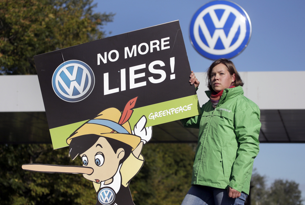 A Greenpeace activist holds a protest poster Friday in front of the Volkswagen factory gate in Wolfsburg, Germany, where the supervisory board met to discuss who to name as CEO after Martin Winterkorn quit the job last week.
