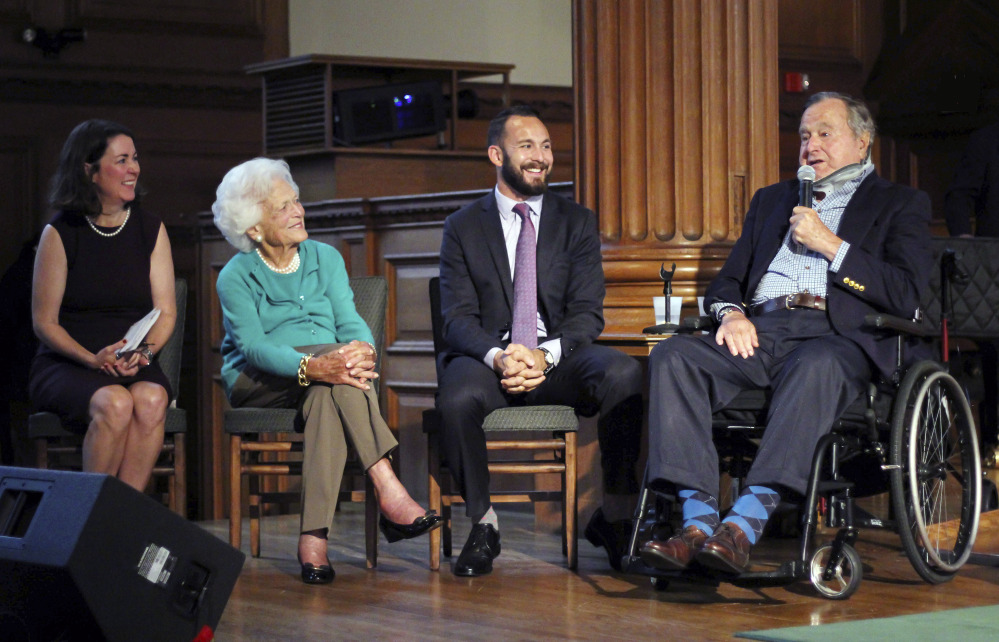 Former President George H.W. Bush, right, speaks Wednesday during a visit to Phillips Academy in Andover, Mass., for a screening of a documentary about the former president. On stage with Bush are Mary Kate Cary, left, executive producer of the documentary, former first lady Barbara Bush and Evan Sisley, an aide to President Bush. Bush, 91, is an alumnus of the class of 1942 at the academy.