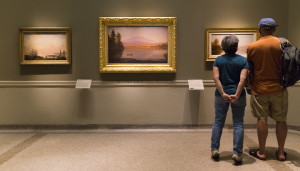 Boston resident Luisa Granitto goes up on her tip-toes next to husband Wendell Smith while admiring “October Mist” by Alfred Bricher in “Directors’ Cut.” Ben McCanna/Staff Photographer