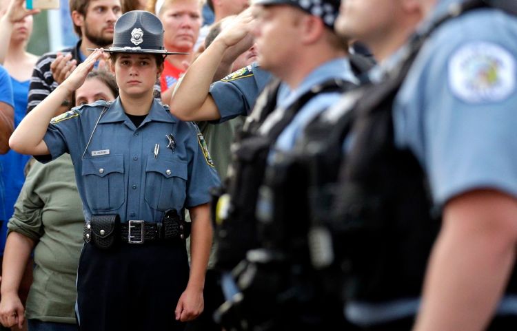 A police Explorer salutes as police officials follow Fox Lake Police Lt. Charles Joseph Gliniewicz's family after a vigil Wednesday in Fox Lake, Ill. The Associated Press