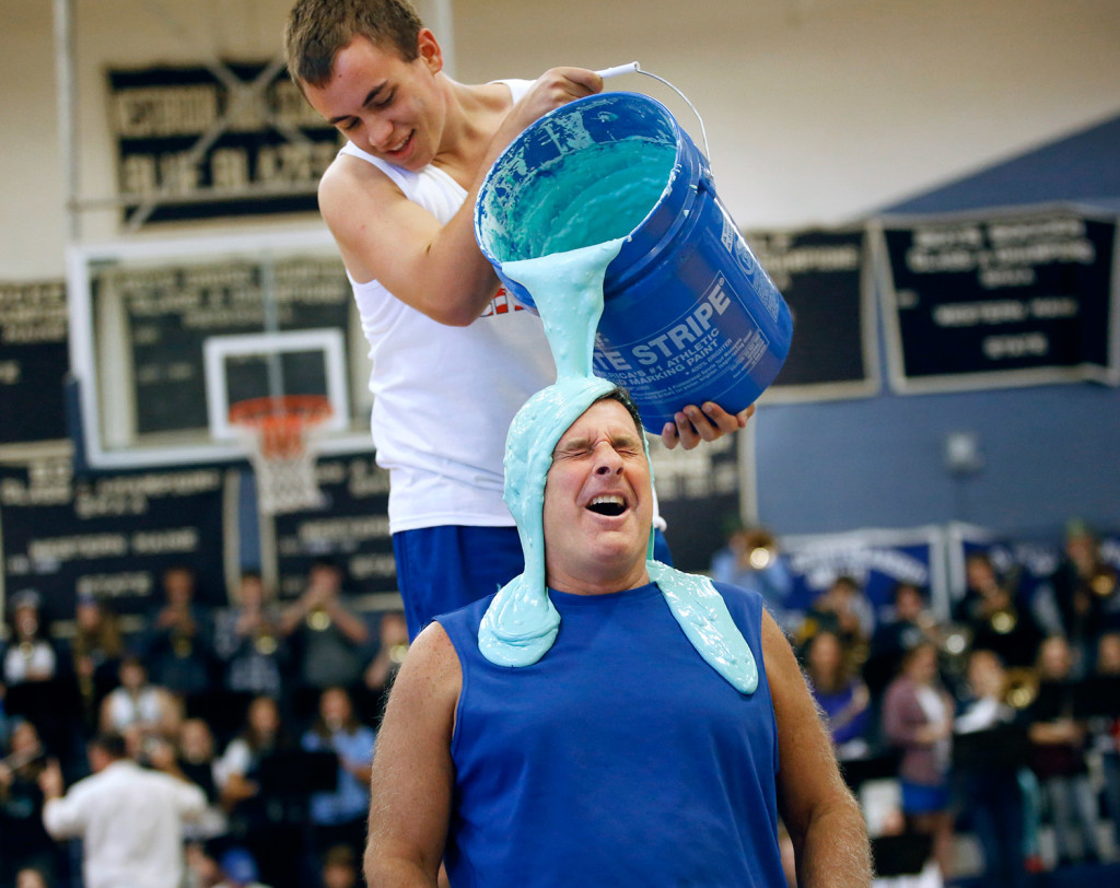 Westbrook High School Principal Jon Ross grimaces as the sliming begins during an annual pep rally at the school Wednesday. Wielding the bucket is senior Josh Miner. As part of fundraiser, money was put in jars corresponding to four schools officials and Ross had the most money in his jar. So he got slimed. (Derek Davis/Staff Photographer)