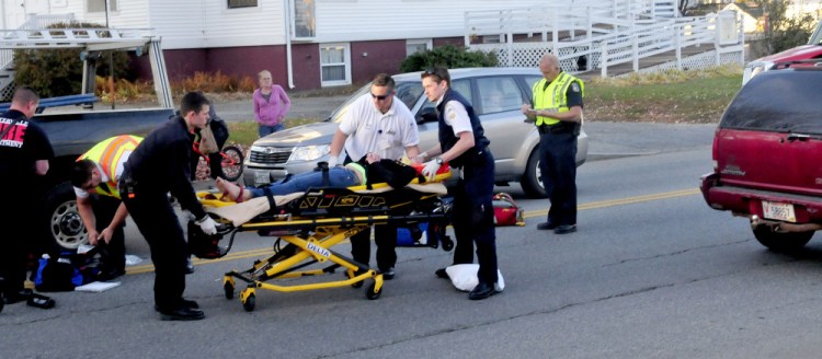 An injured teenager is carried to an ambulance after she ran into an SUV while crossing Silver Street in Waterville on Wednesday. The girl, who was taken to Inland Hospital, ran out into the street from between two vehicles that were stopped at a red light, police and witnesses said.