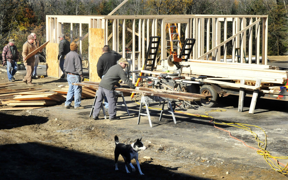 Homeowner Jeff Chadbourne, center, watches as friends and volunteers help build a new barn at his farm on Monday. Fire destroyed the old barn last week, killing several farm animals.