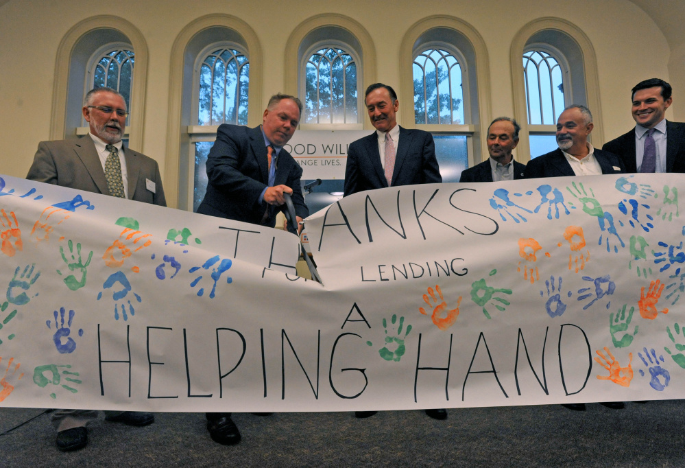Jack Moore, left center, interim president of the Maine Academy of Natural Sciences, cuts the ceremonial banner with Rob Moody, left, interim president of Good Will-Hinckley, and Greg Powell, center, Good Will-Hinckley board chairman, during an inauguration ceremony Wednesday at the former Moody School at the Good Will-Hinckley campus in Hinckley. The building, which recently underwent $7 million worth of renovation and expansion, is being touted as Maine’s first fully solar-powered academic building. The expansion will allow the charter school to more than double its current enrollment.