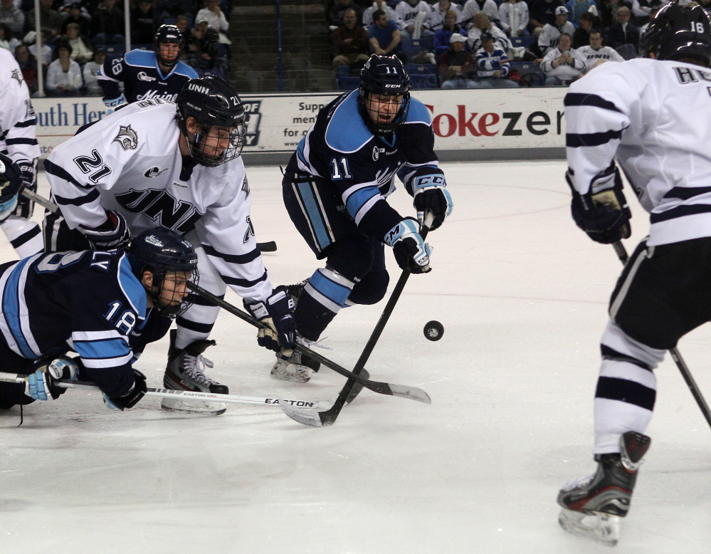 New Hampshire’s Nick Sorkin (21) works to control a face-off against Maine’s Jon Swavely (18) and Steven Swavely (11)  in 2013. Steven Swavely is the Black Bears' captain this season.