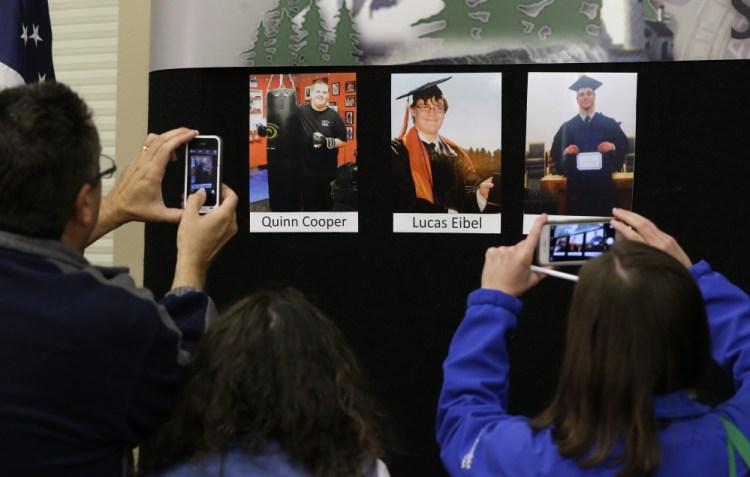 Reporters copy photographs of three of the victims of the mass shooting at Umpqua Community College that were displayed at a news conference Friday in Roseburg, Ore.  In the photos, from left, are Quinn Cooper, 18, Lucas Eibel,18,  and Jason Johnson, 33.