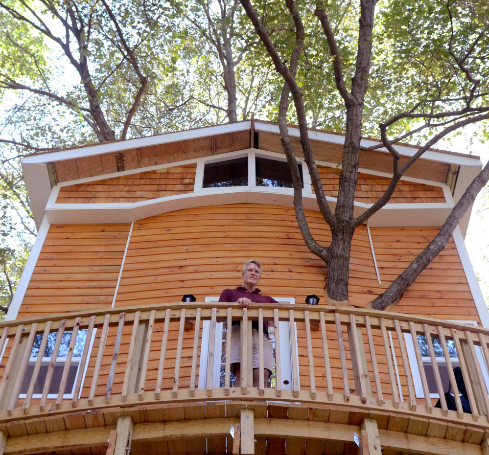 Jay Hewitt stands on the deck of a treehouse he built for his grandchildren in his backyard in Attleboro, Mass. The fully enclosed structure, made from salvaged leftovers, features a family room, loft for sleepovers and built-in spiral slide.