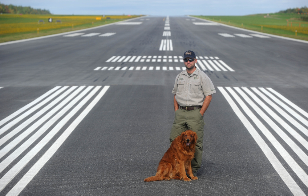Randy Marshall, airport manager at Robert LaFleur Municipal Airport, stands with his dog Molly on the newly renovated runway at the city-owned airport in Waterville.