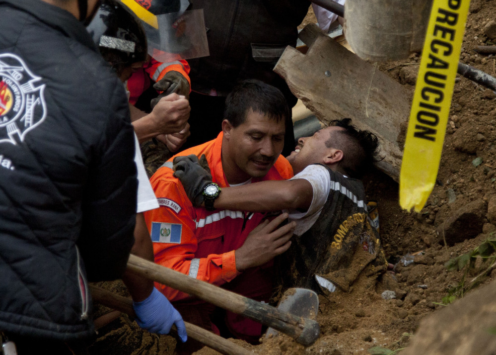 A worker is rescued after he was trapped at the site of a mudslide in Cambray, near Guatemala City, on Saturday. The hill that towers over Cambray collapsed late Thursday.
