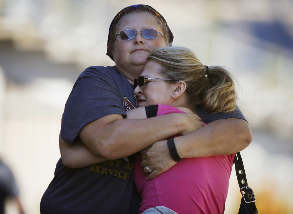 People embrace while preparing to get driven to Umpqua Community College to collect belongings Friday in Roseburg, Ore.