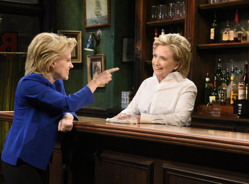 Kate McKinnon, left, portrays Hillary Clinton, and Hillary Clinton, right, portrays Val, a bartender, during a sketch on “Saturday Night Live” in New York. 