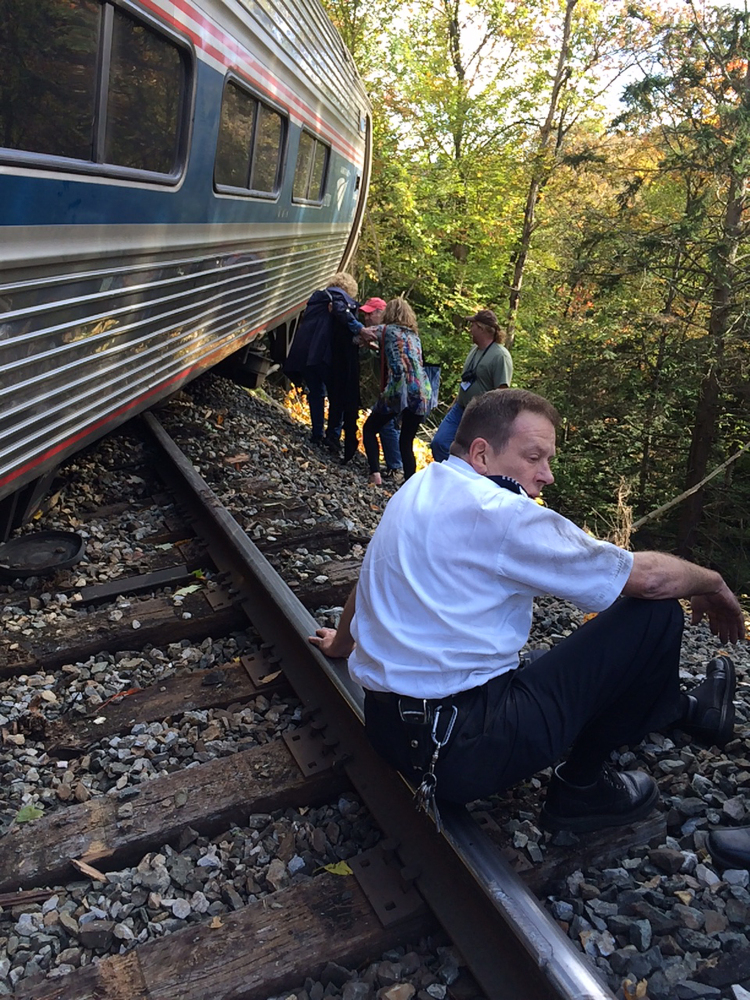 A train conductor sits next to an Amtrak train after it derailed Monday near Roxbury, Vt., about 20 miles southwest of Montpelier.