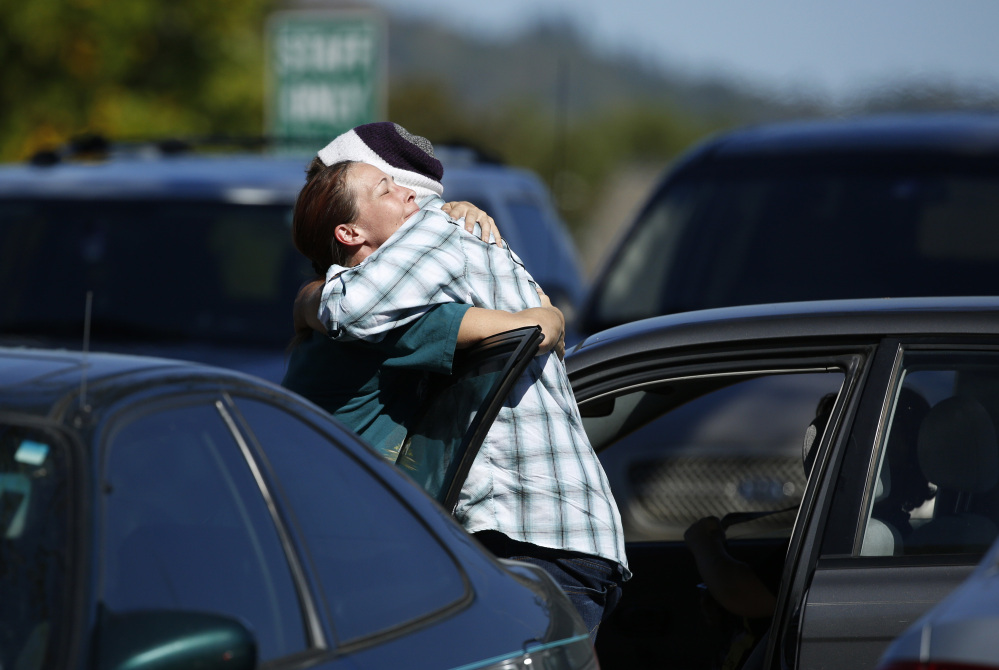 Student Mathew Downing, right, is comforted by an unidentified woman as they return to Umpqua Community College, Monday, in Roseburg, Ore.