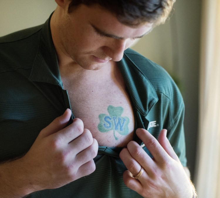 Travis Walsh has a tattoo over his heart of the patch that the University of Maine hockey team wore in honor of their late coach, Shawn Walsh, Travis’ father.
